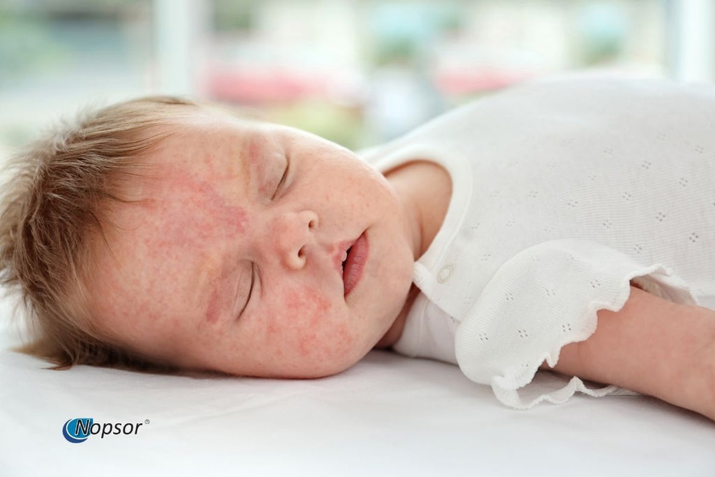 Baby lying on a white surface with a blurred colorful background