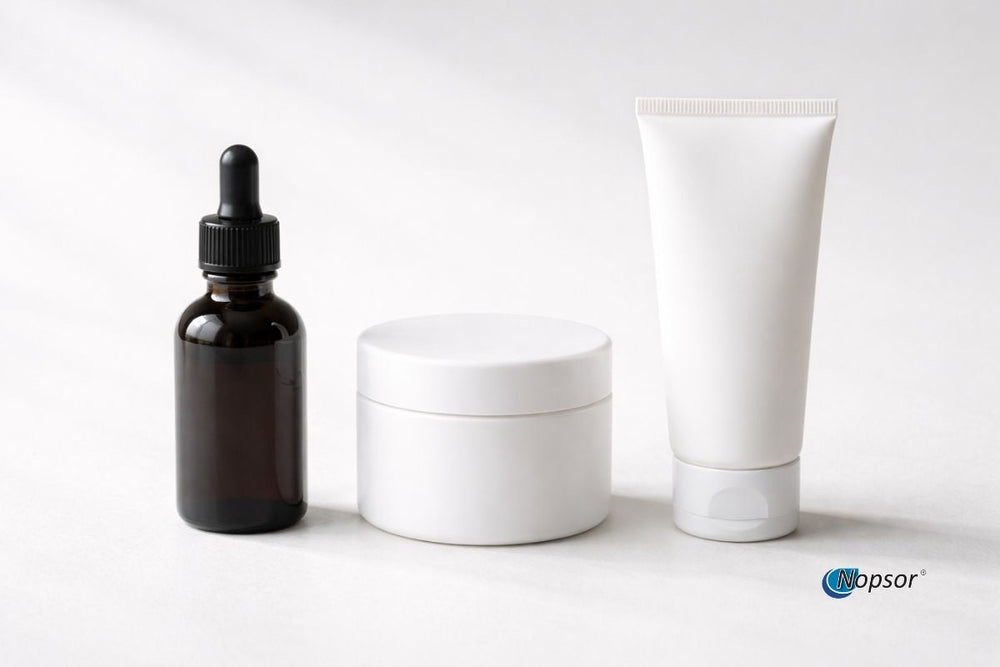 Cosmetic products including a dropper bottle, jar, and tube on a white background