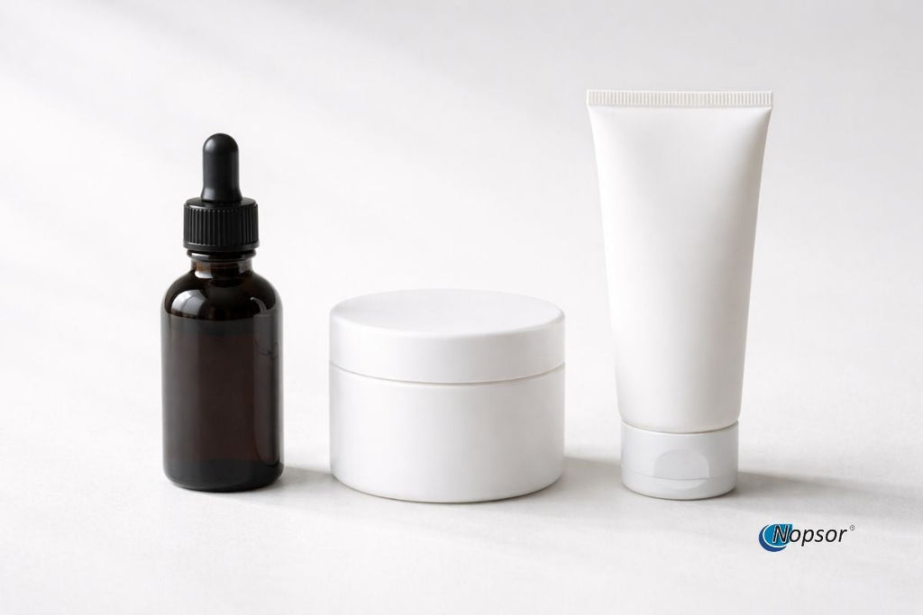 Cosmetic products including a dropper bottle, jar, and tube on a white background