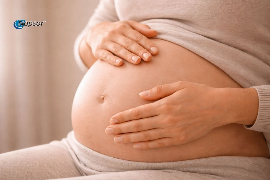 Pregnant person holding their belly with a soft background